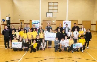Participants of the United Youth Initiative pose for a photo in a school gym