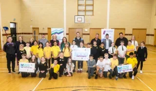 Participants of the United Youth Initiative pose for a photo in a school gym