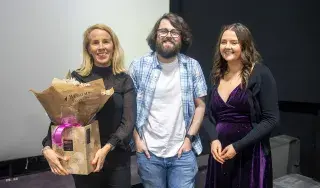 Programme Director Sarah McCann being presented with a bouquet by 4th year class reps Cian Gibson and Laura Byrne